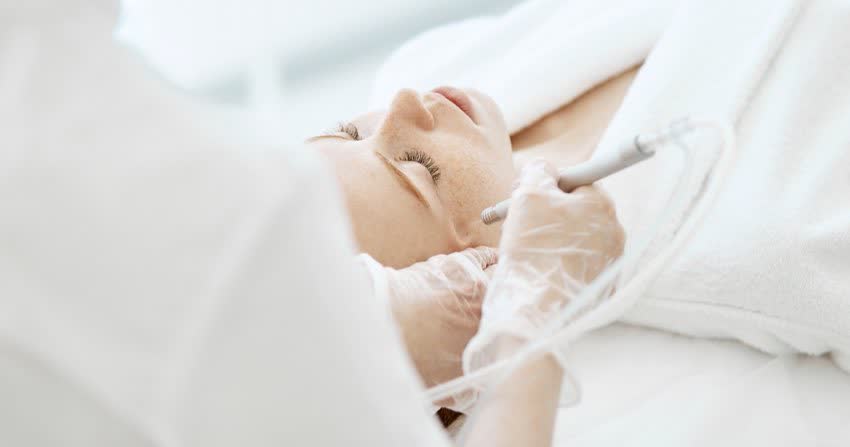 Dermatologa che esegue trattamento di peeling per cicatrici da acne sul volto