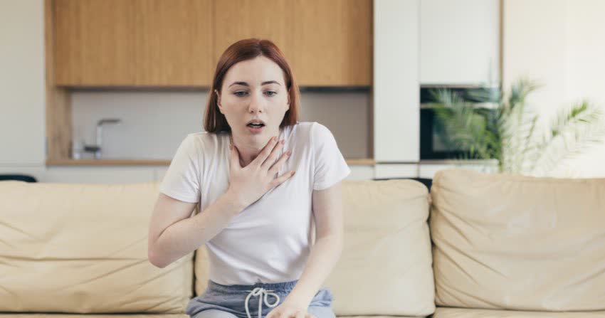 Donna seduta su un divano con difficoltà a respirare caratteristica della dispnea da ansia