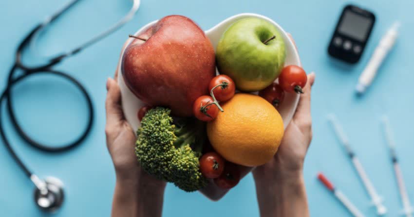 Piatto di frutta e verdura su sfondo con stetoscopio e punture di insulina per diabetici