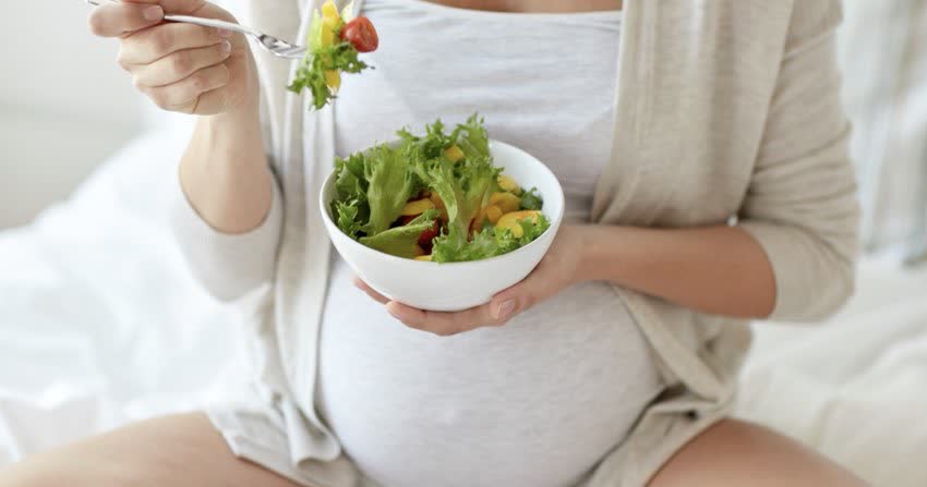 Donna incinta che mangia un'insalata
