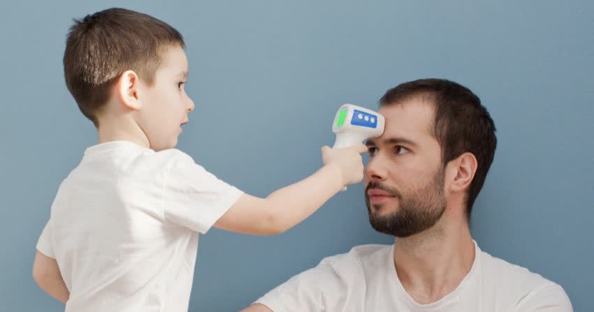 Bambino che misura febbre su fronte del papà