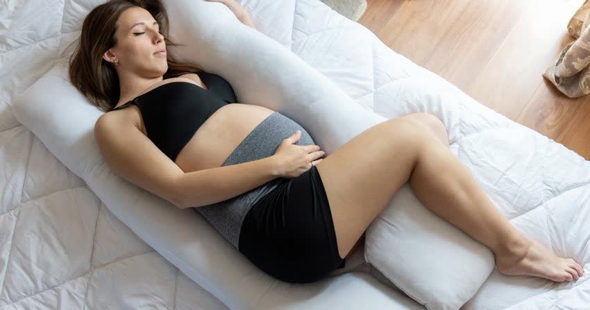 Donna in gravidanza che dorme serenamente grazie a cuscino da gravidanza