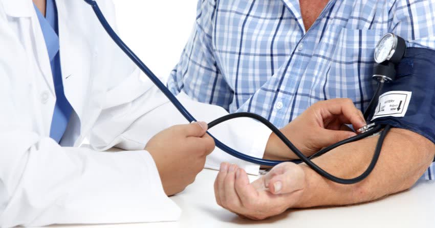 Medico che misura pressione arteriosa in uomo anziano