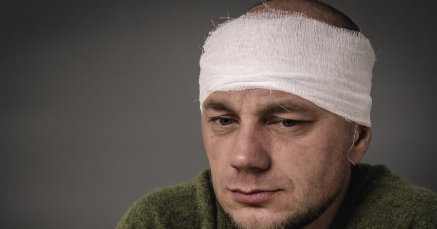 Uomo con benda sulla testa ad indicare trauma cranico