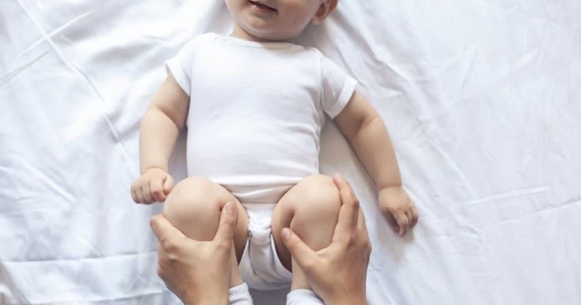 Mamma che massaggia gambine neonato per agevolare i movimenti intestinale
