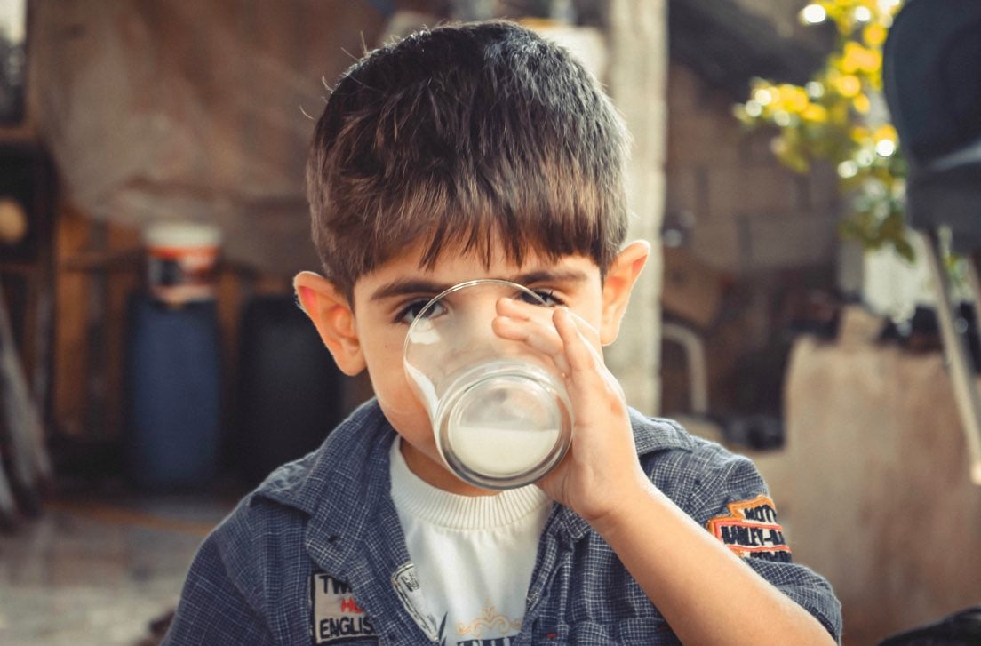 Bambino che beve latte, alimento ricco di vitamina B2