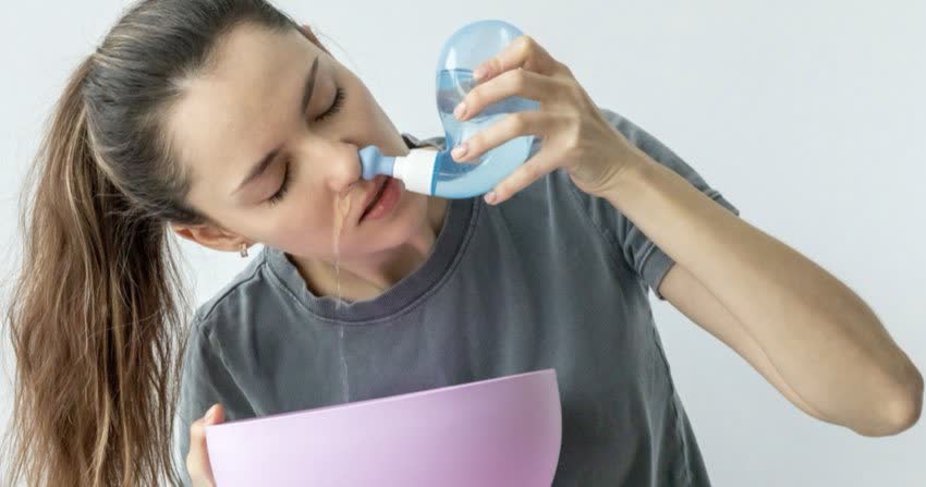 Giovane donna che esegue lavaggi nasali con acqua fisiologica