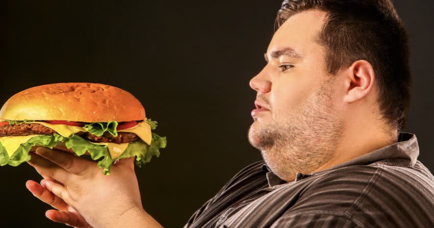 Uomo obeso con alimenti ipercalorici