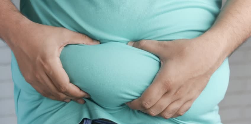 Foto di persona obesa che si tiene la pancia per rappresentare il bypass gastrico