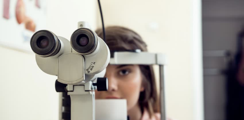 Foto di una donna ragazza in ambulatorio oculistico mentre si approccia a svolgere un esame oculistico per scongiurare la presenza di glaucoma