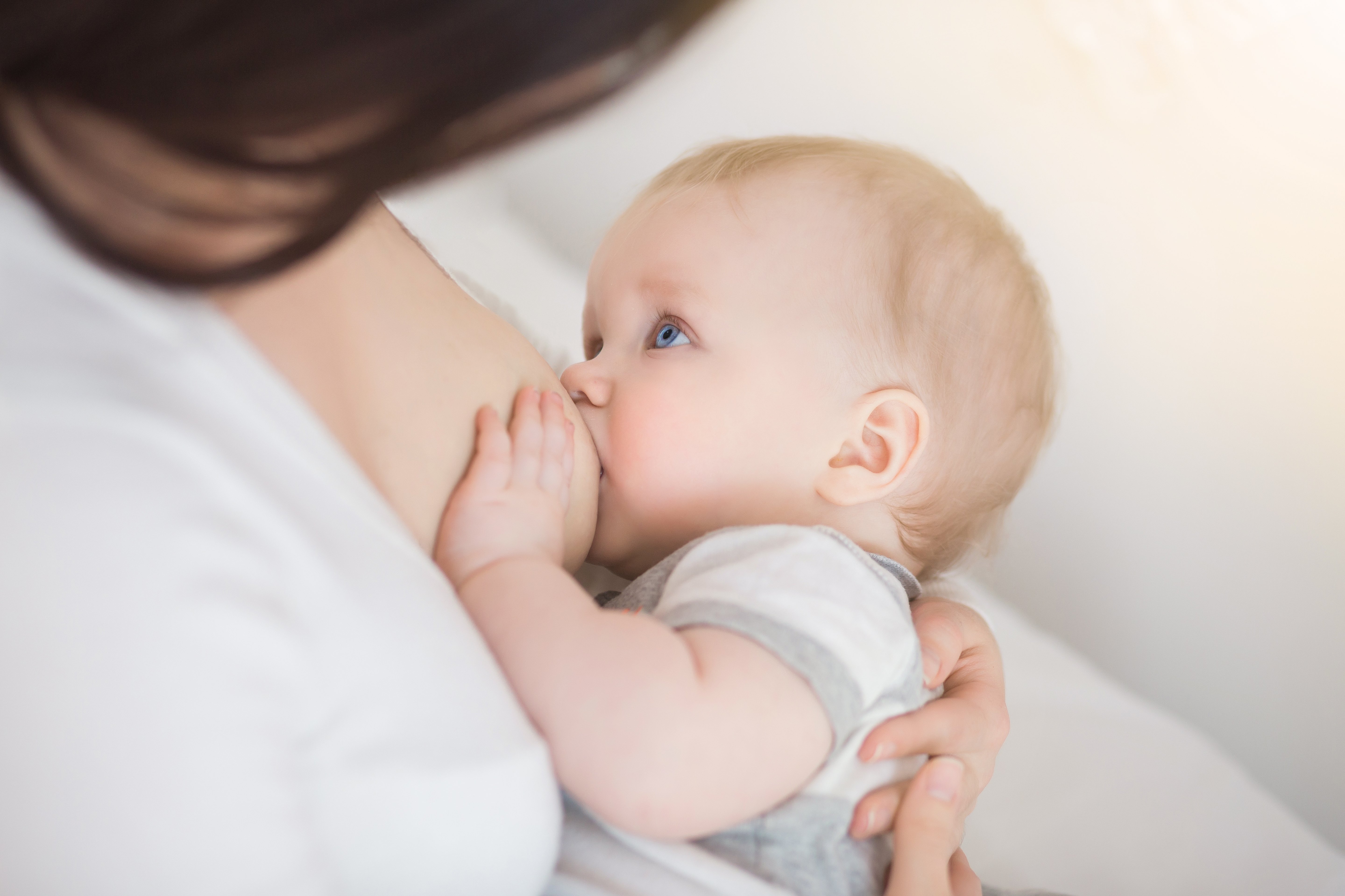 Primo piano di un bambino mentre viene allattato al seno dalla mamma